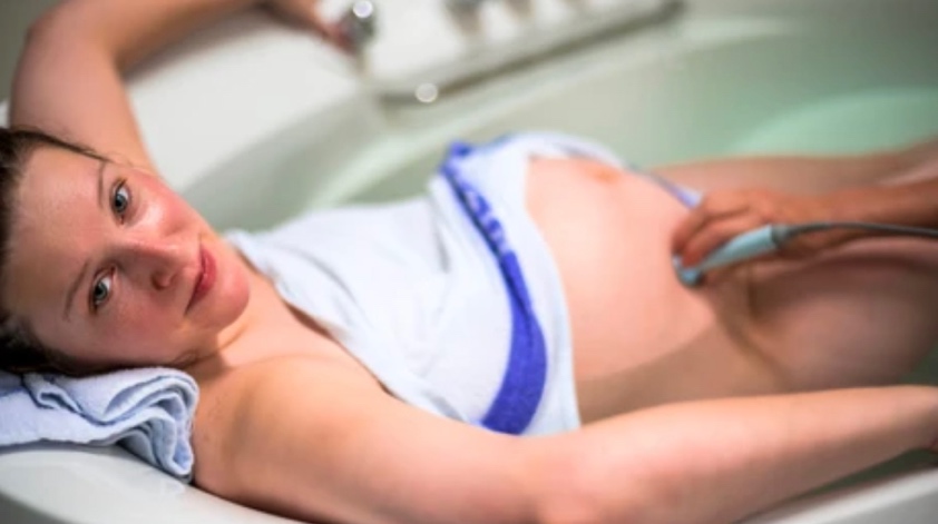 Woman Relaxing in Bath inbetween Contractions whilst Being Monitored